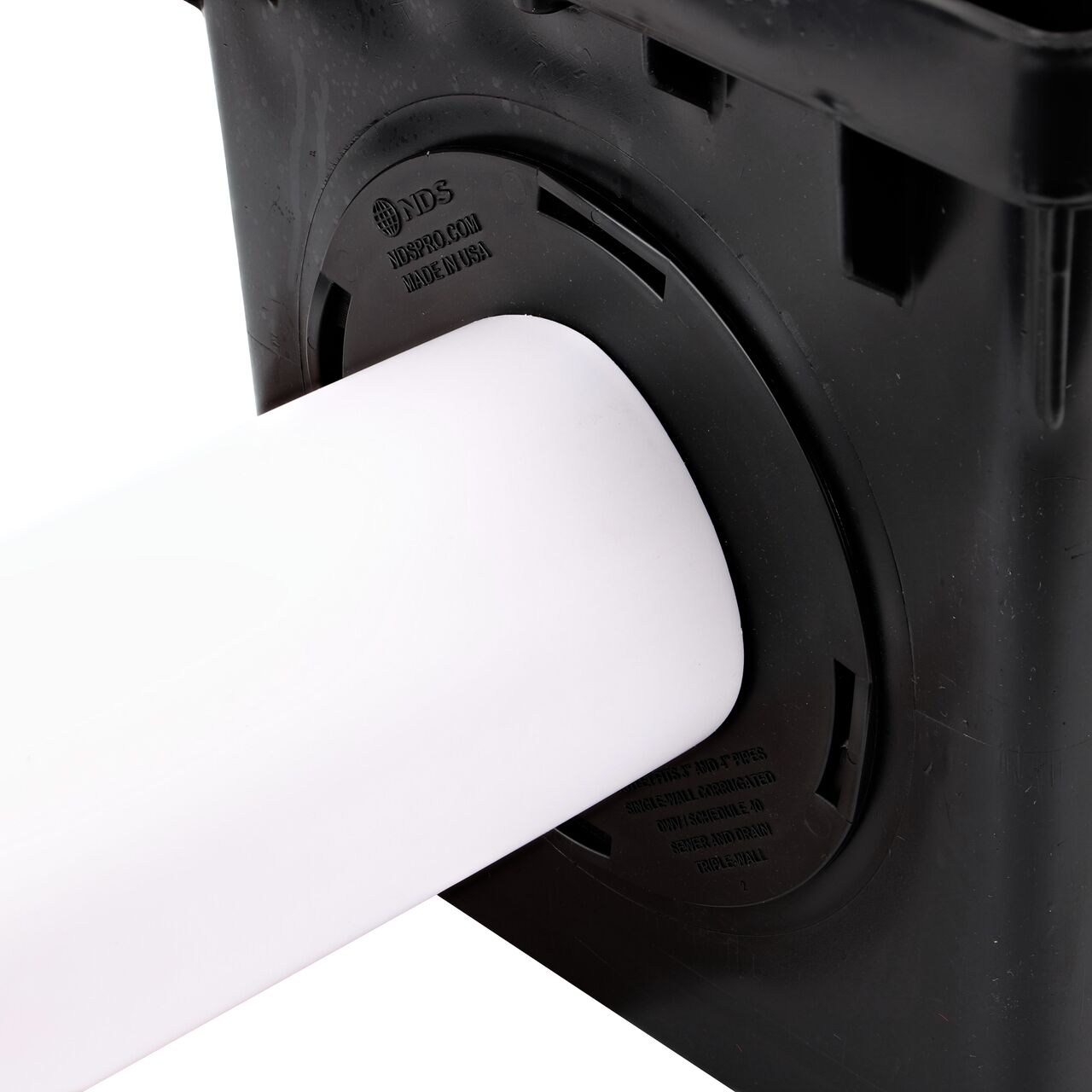 Closeup of the retail (NDS 1244*) Outlet Adapter for Catch Basin Drain which fits 3 in. & 4 in. Drain Pipes, with a 4 in. S&D pipe installed on the 3-outlet 12 in. Catch Basin Drain (NDS 1203)