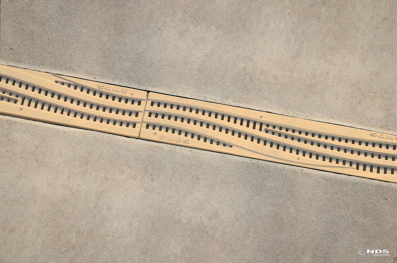 NDS Spee-D® Channel Drain Grate, Decorative Wave Design in Sand Plastic installed in a drainage system (NDS 253S)
