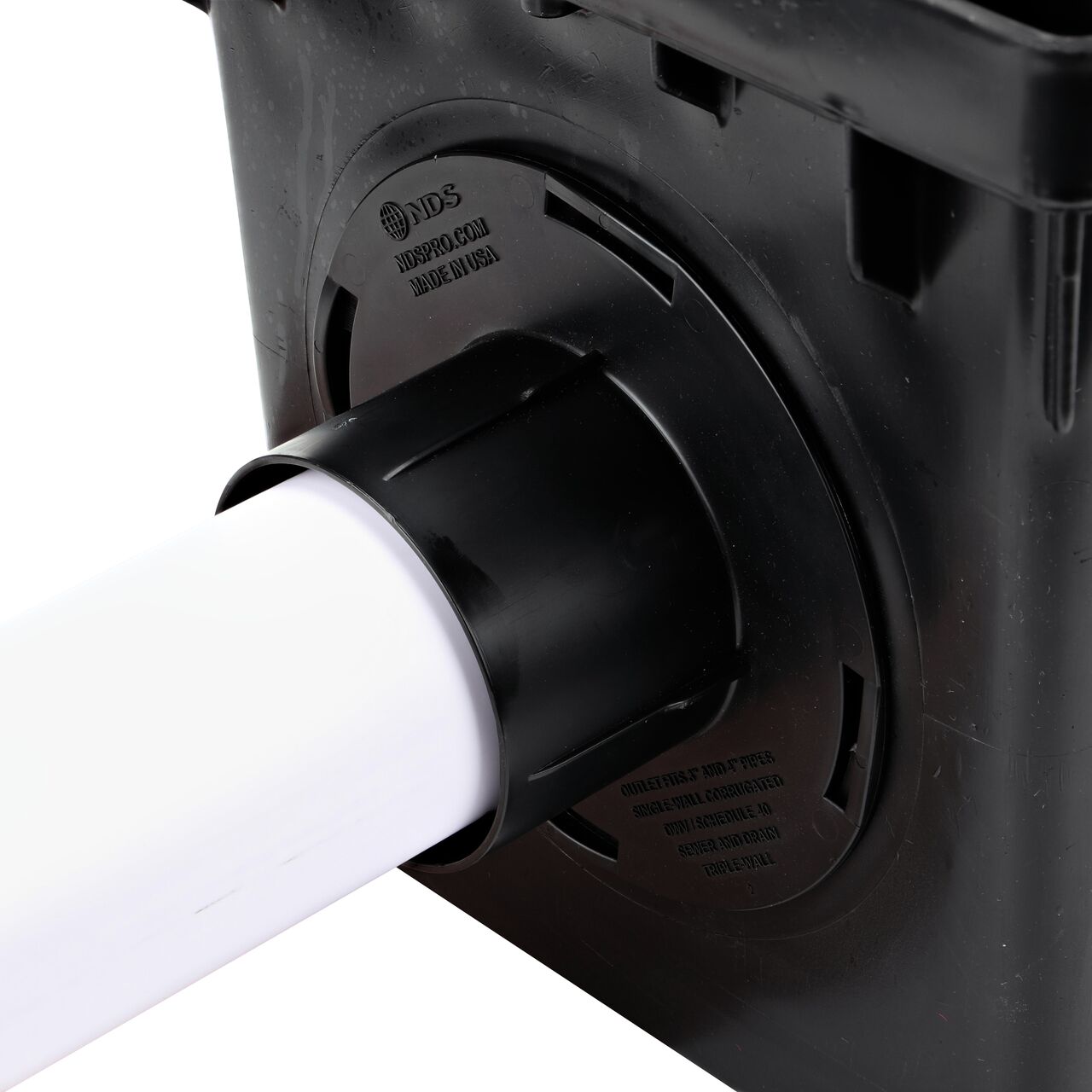 Closeup of the retail (NDS 1244*) Outlet Adapter for Catch Basin Drain which fits 3 in. & 4 in. Drain Pipes, with a 3 in. S&D pipe installed on the 3-outlet 12 in. Catch Basin Drain (NDS 1203)