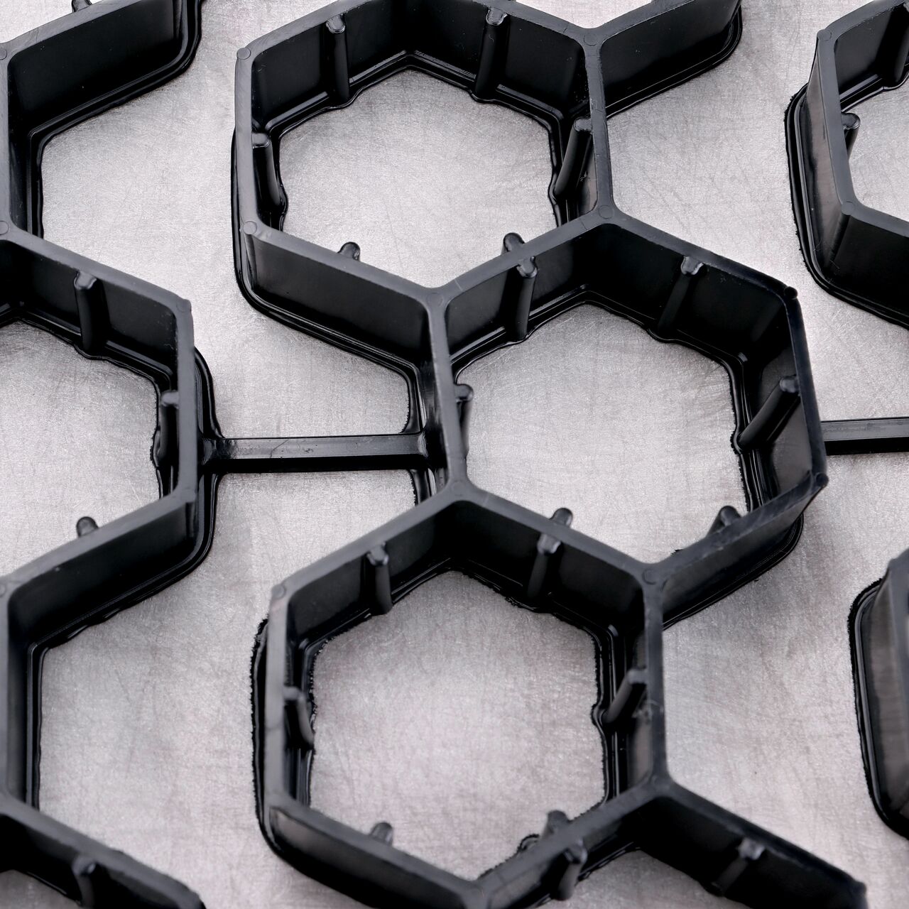 Closeup view of the interconnected hexagonal cells with shared walls which provide strength in the Black NDS EZ Roll® Gravel Pavers (NDS GP4X150)