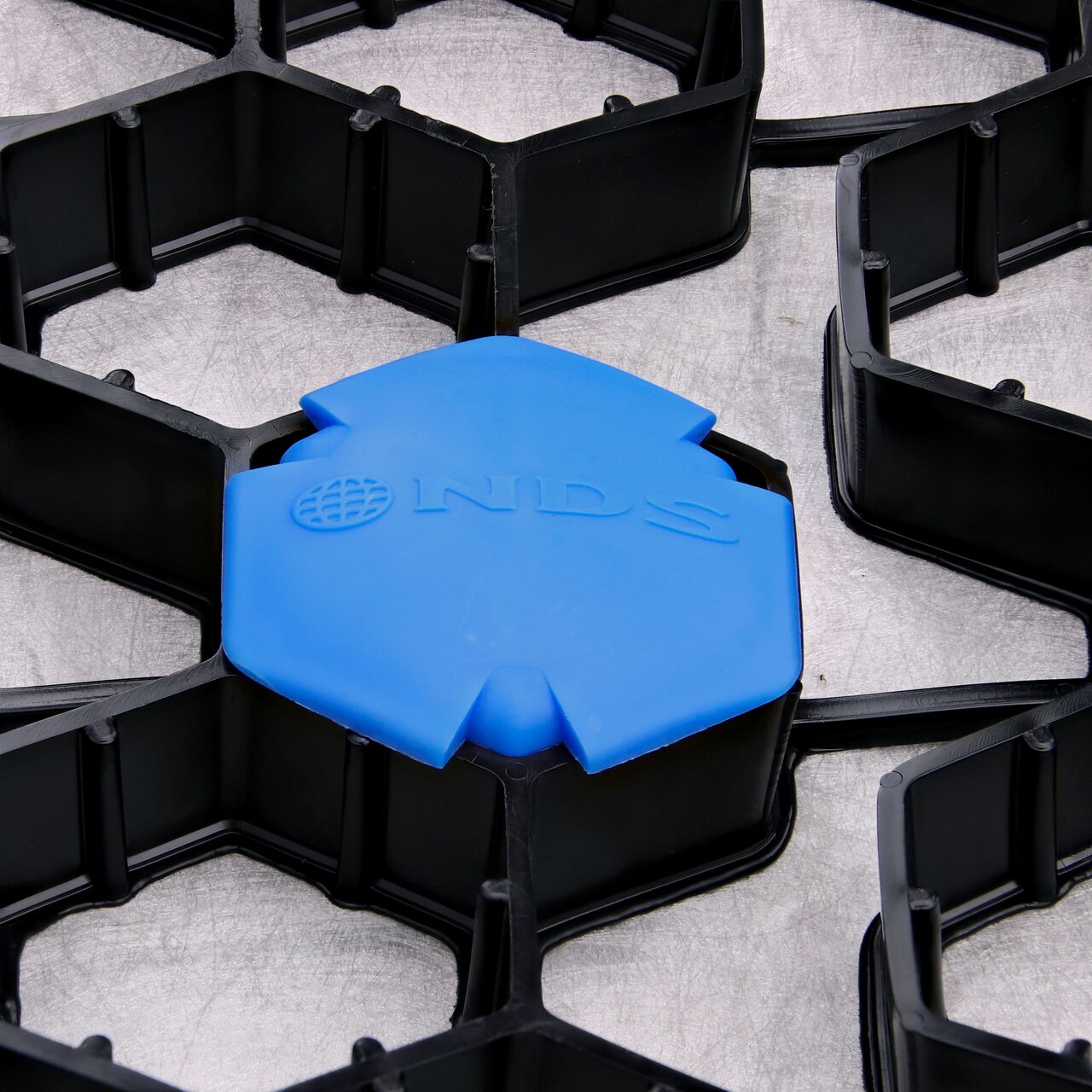 Closeup of one Blue NDS EZ Marker™ Parking Delineators (NDS EZMARKER) installed in the NDS EZ Roll® Gravel Pavers (NDS GP4X150)
