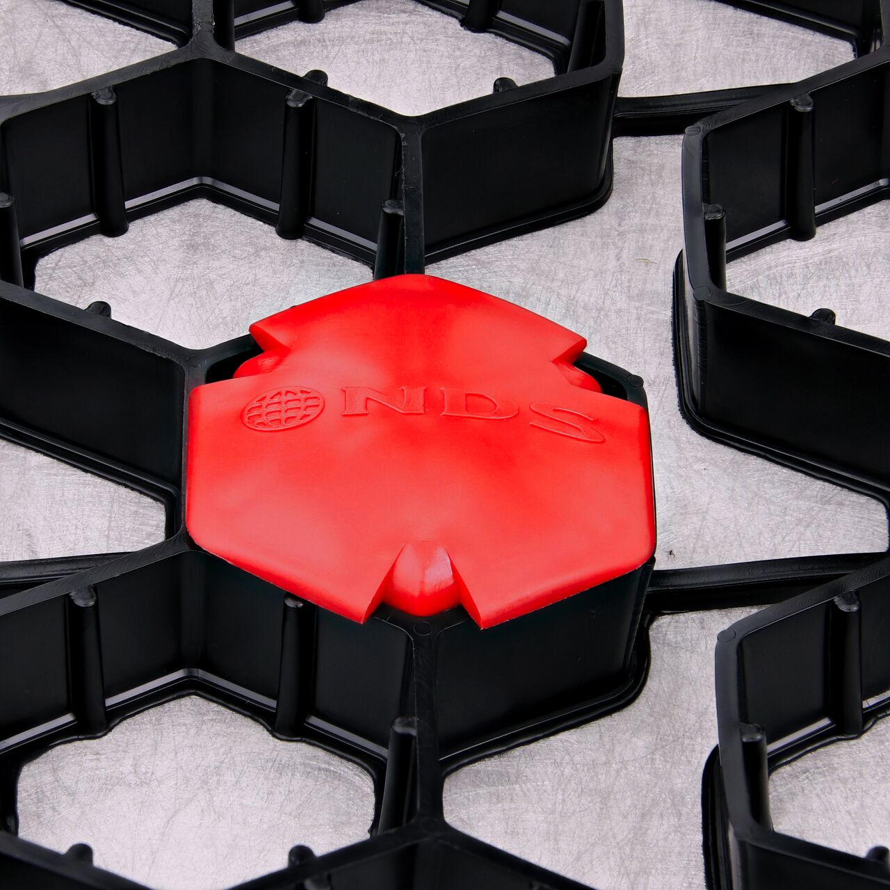 Closeup of one Red NDS EZ Marker™ Parking Delineators (NDS EZMARKER) installed in the NDS EZ Roll® Gravel Pavers (NDS GP4X150)