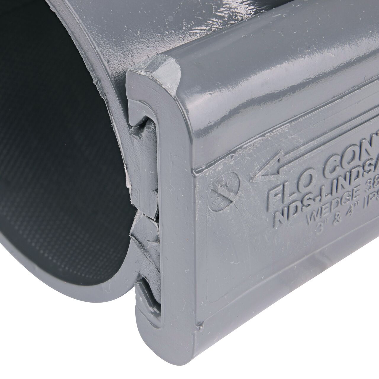 Closeup of the wedge installed securely on the NDS Clamp-It™ Rigid PVC Saddle with 1-1/2 in. slip connection on top (NDS 453015) for 3 in. PVC pipe
