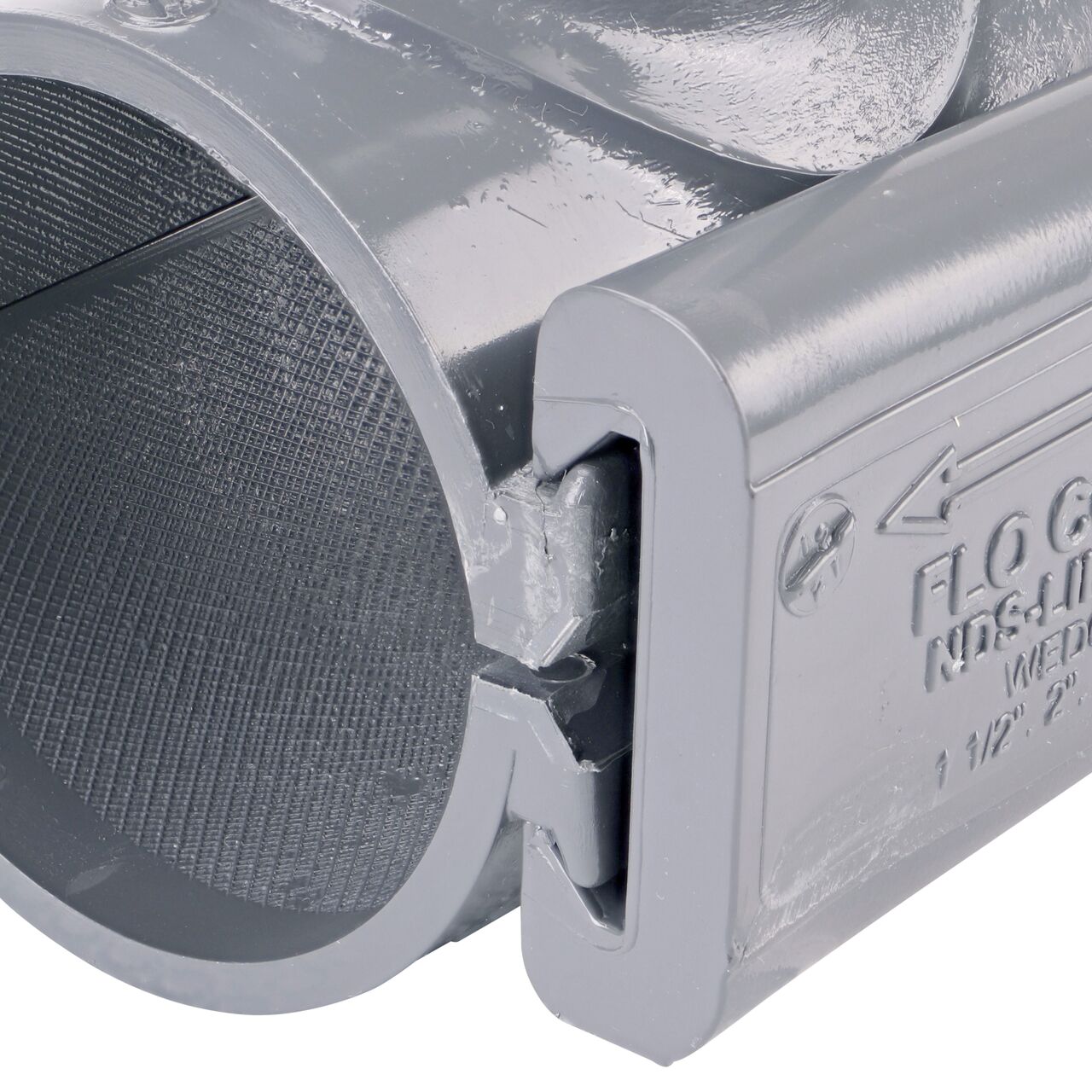 Closeup of the wedge installed securely on the NDS Clamp-It™ Rigid PVC Saddle with 1-1/2 in. slip connection on top (NDS 432515) for 2-1/2 in. PVC pipe