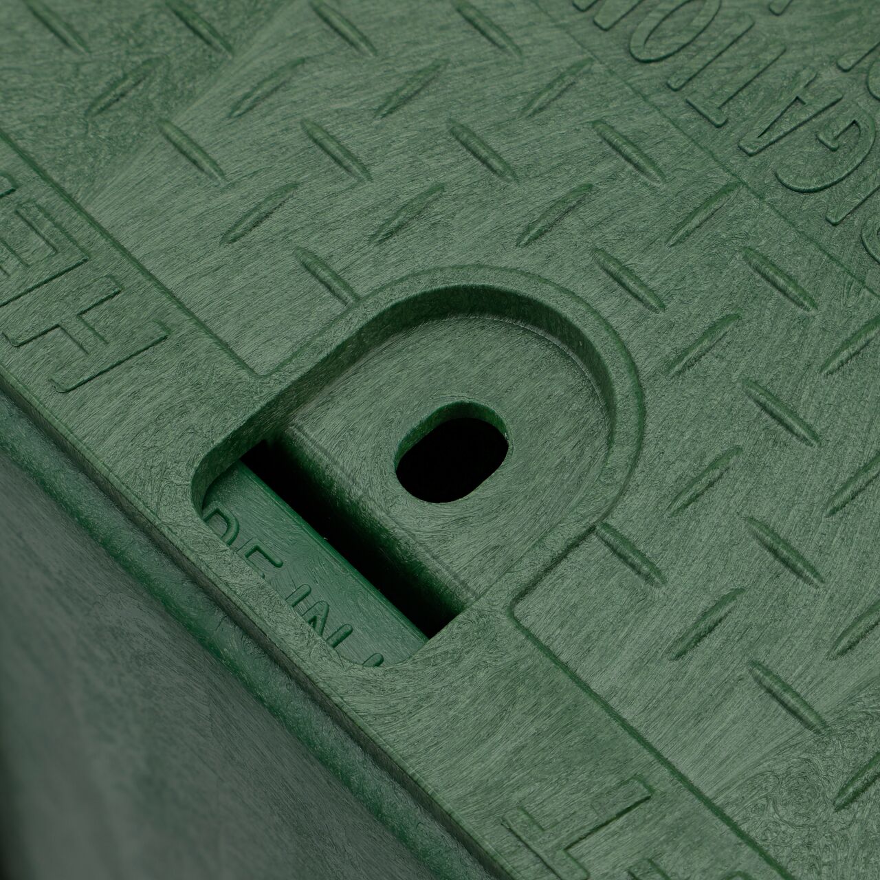 Closeup view of the traditional bolt hole on the Green NDS 14 in. X 19 in. Rectangular Pro-Spec® Series Valve Box (NDS 314BCB) for securing valve lid or cover to the valve box
