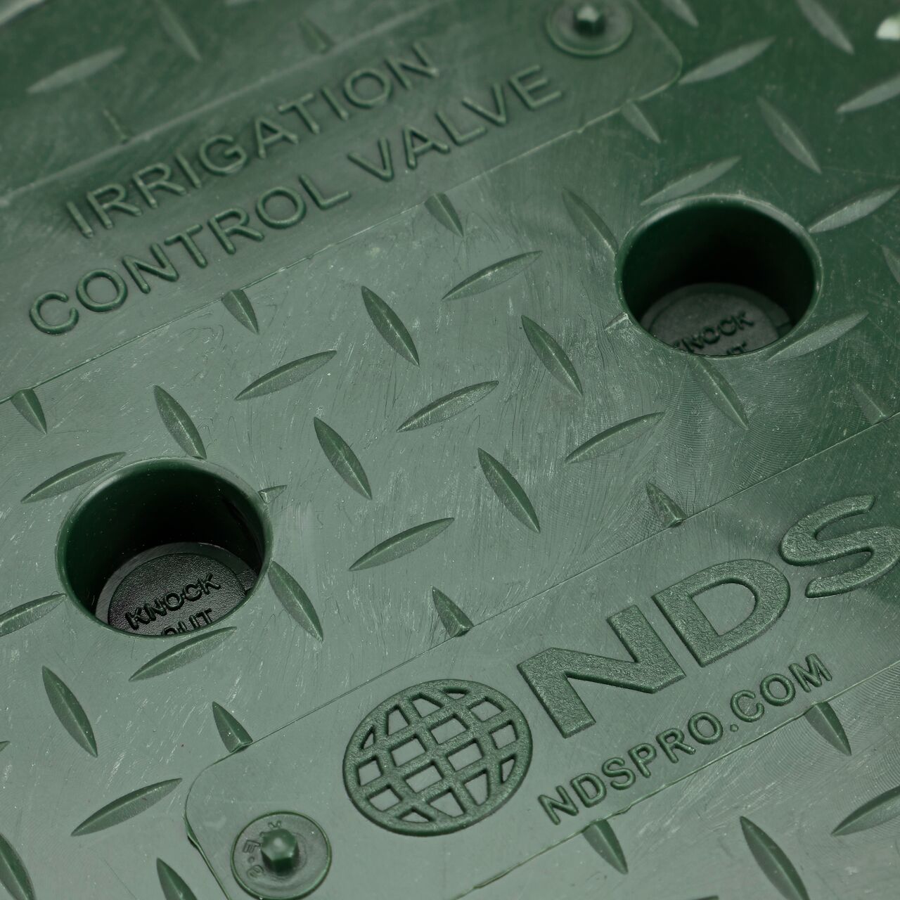 Closeup view of the Green Irrigation Control Valve markings and the fingerholes on the cover for the NDS 6 in. Round Standard Series Valve Box (NDS 2107BC) showing the option to knockout the fingerholes if required