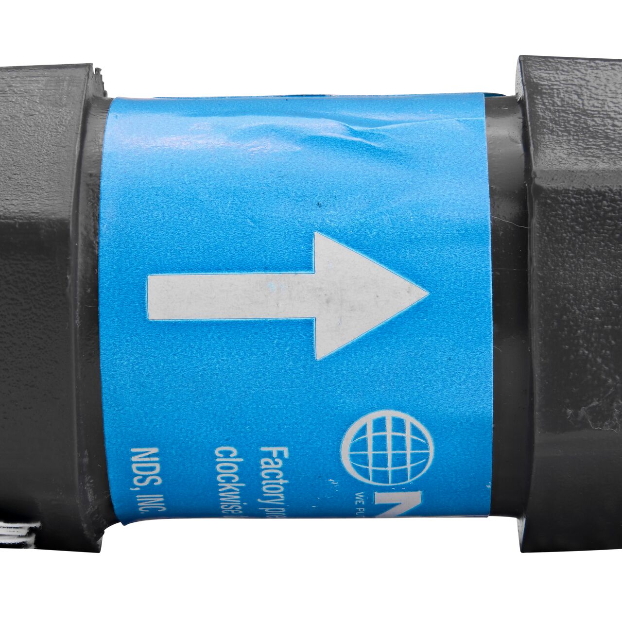 Closeup of the label marking the water flow direction of on the NDS Gray 1/2 in. IPS FPT X FPT PVC Adjustable Inline Spring Check Valve (NDS CV-0500-FF)