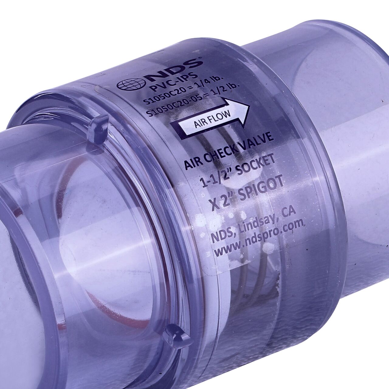 Closeup of the label showing the water flow directon on the NDS White 1-1/2 in. IPS S x 2 in. Spigot PVC Air Check Valve (NDS S1050C20)