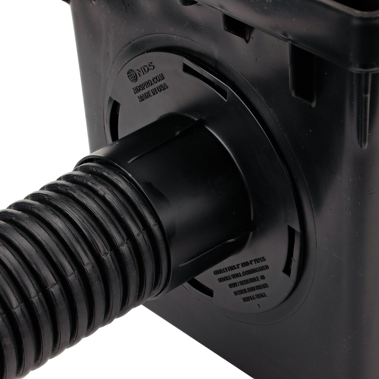 Closeup of the retail (NDS 1244*) Outlet Adapter for Catch Basin Drain which fits 3 in. & 4 in. Drain Pipes, with a 3 in. single-wall corrugated pipe installed on the 3-outlet 12 in. Catch Basin Drain (NDS 1203)