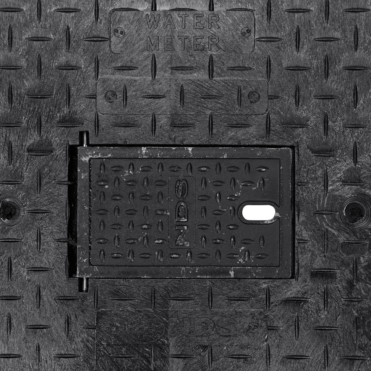 Closeup view of the Water Meter markings and Cast Iron reader door on the Black Water Meter Drop-In cover for the NDS 17 in. X 30 in. Rectangular Pro Series Meter Cover (NDS 123CDMCIF)