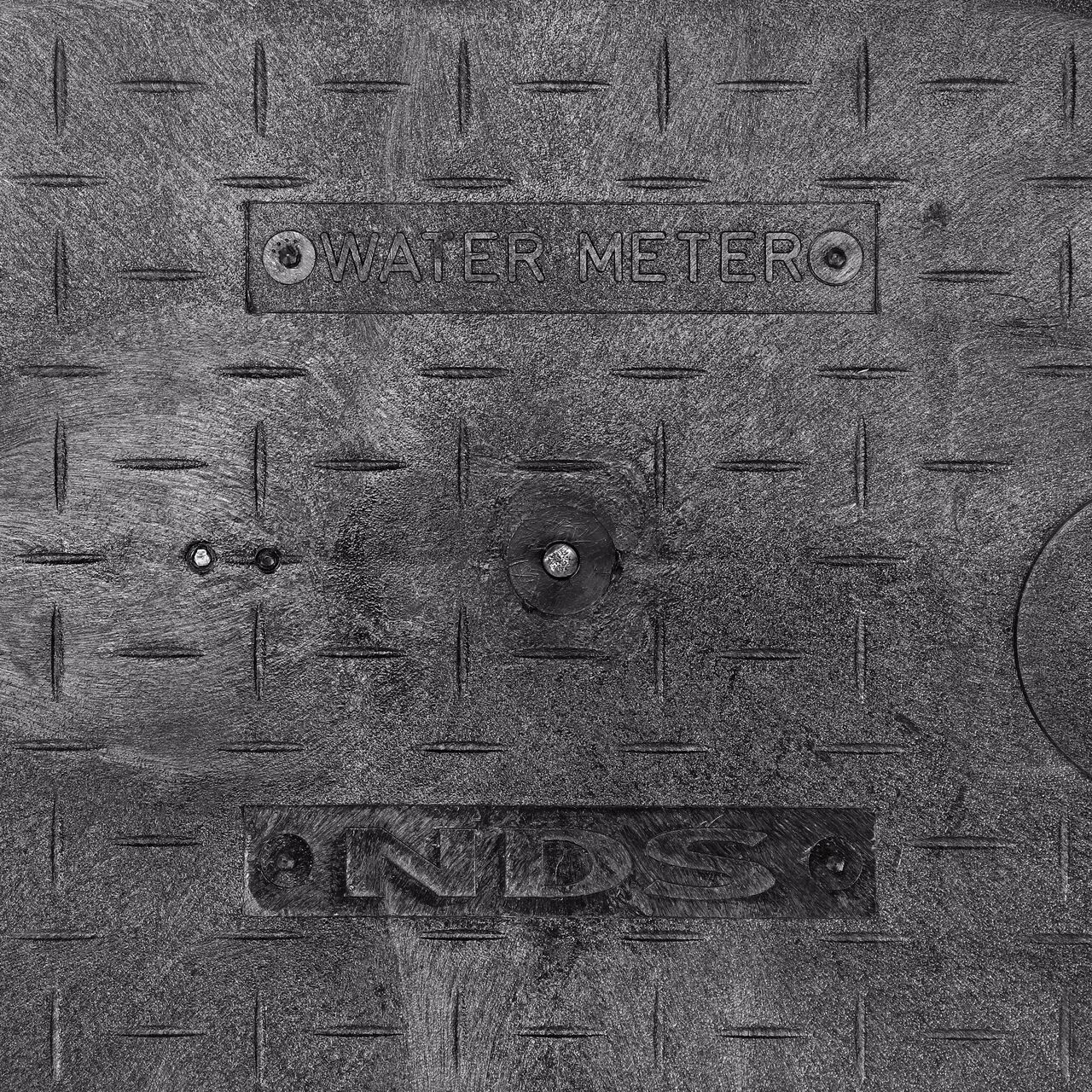 Closeup view of the Water Meter markings on the Black Water Meter Overlapping cover for the NDS 14 in. X 19 in. Rectangular Standard Series Meter Cover (NDS D1200-OLLOCBLD)