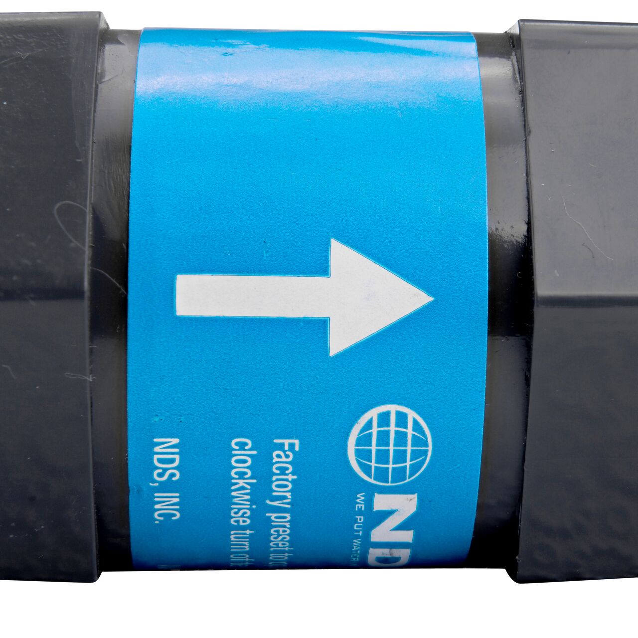 Closeup of the label marking the label flow of the NDS Gray 1 in. IPS FPT X FPT PVC Adjustable Inline Spring Check Valve (NDS CV-1000-FF)