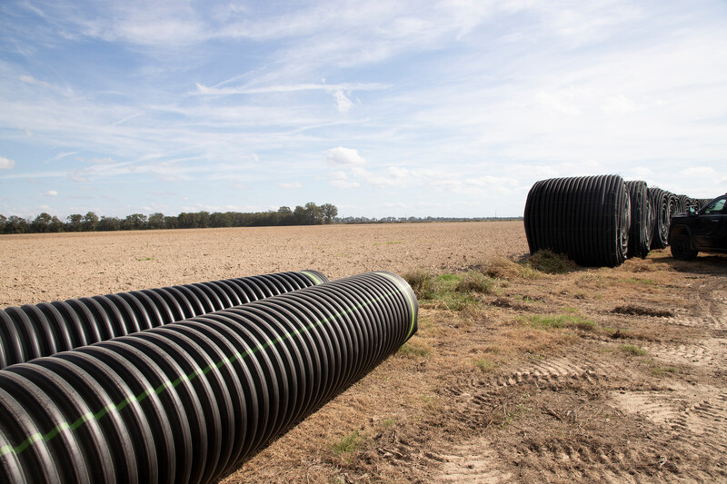 Sticks of Pipe In Field with line of Maxi Coil