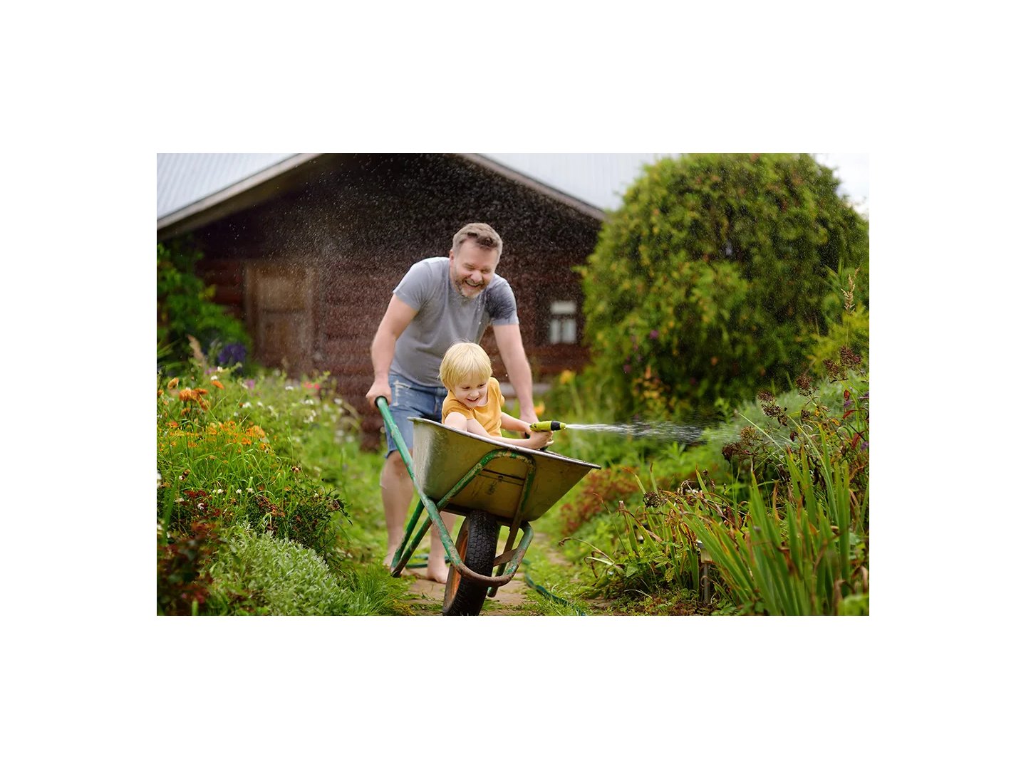 Boy Watering Plants with Hose